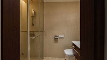 Un baño moderno con ducha envuelta en vidrio, inodoro y tocador con espejo.
