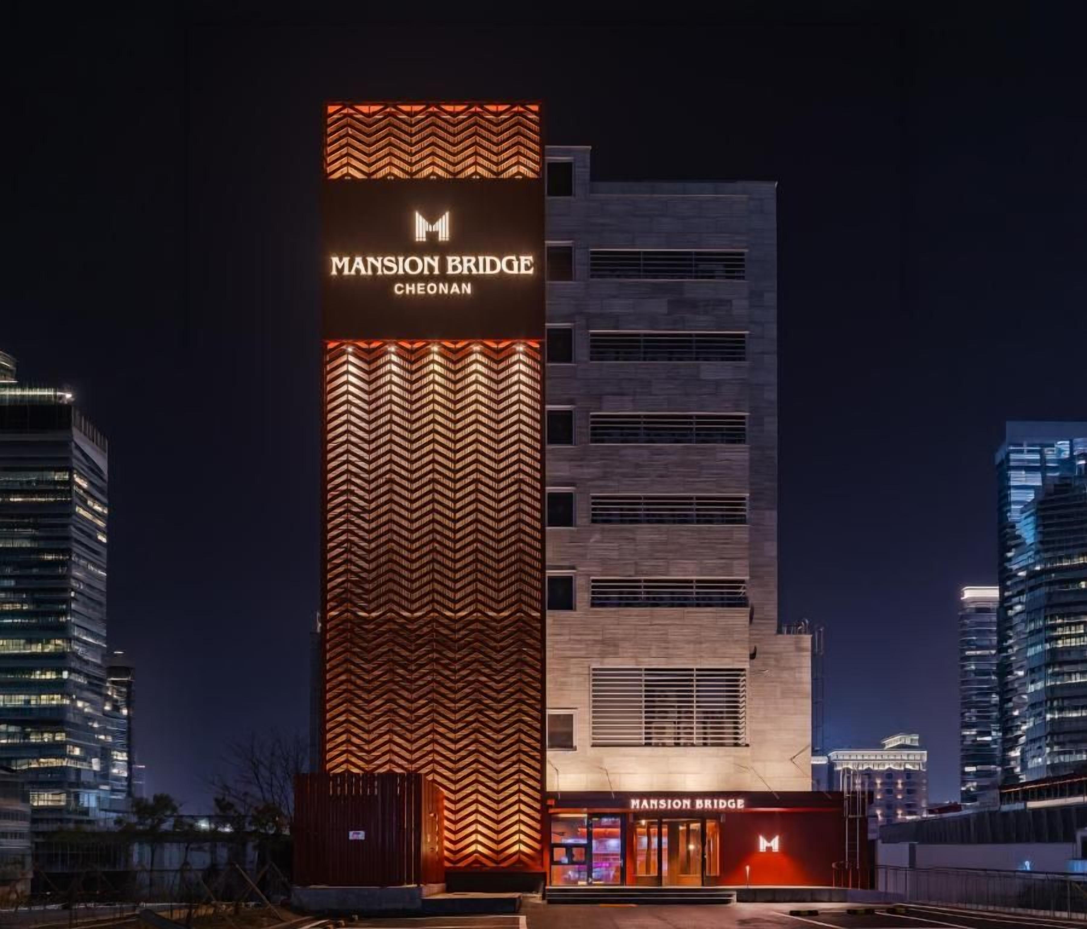 Un edificio moderno con un llamativo letrero que dice 'Mansion Bridge', que presenta un diseño de estampada en zigzag en la fachada.