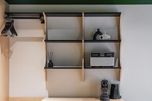 A kitchen with a black countertop, a radio, a coffee maker, and a hanging rack with black items. - Mansion Bridge Cheonan (Cheonan)