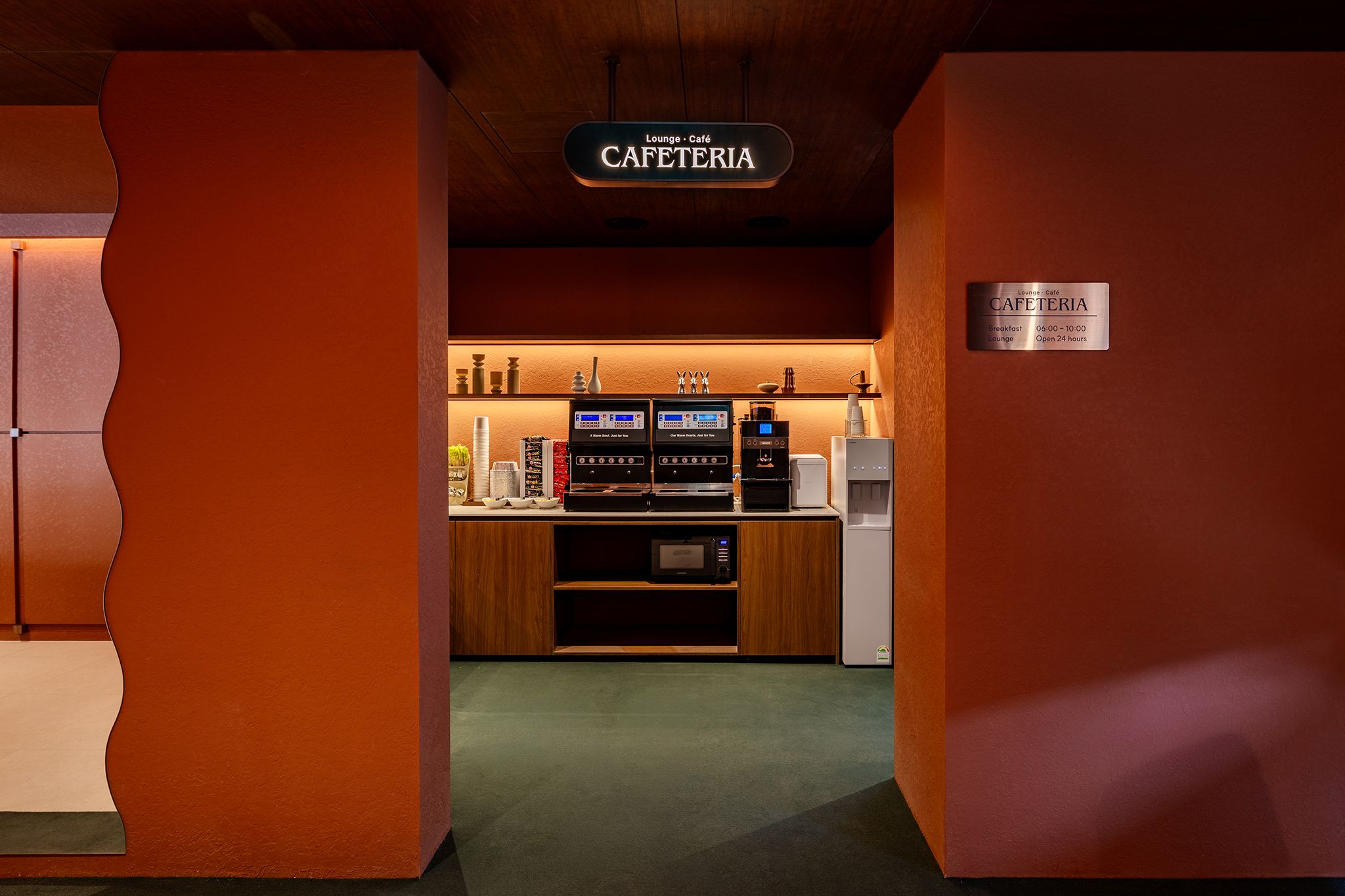 Un área de café con un letrero que indica que es un salón y cafetería, equipada con máquinas de café y un microondas.