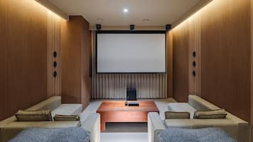 Un cine en casa con una pantalla grande, asientos cómodos y paneles de madera.