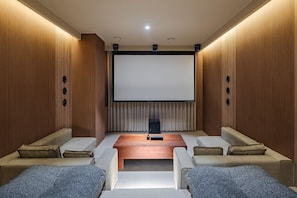 Un cine en casa con una pantalla grande, asientos cómodos y paneles de madera.