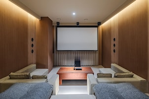 Un cine en casa con una pantalla grande, asientos cómodos y paneles de madera.