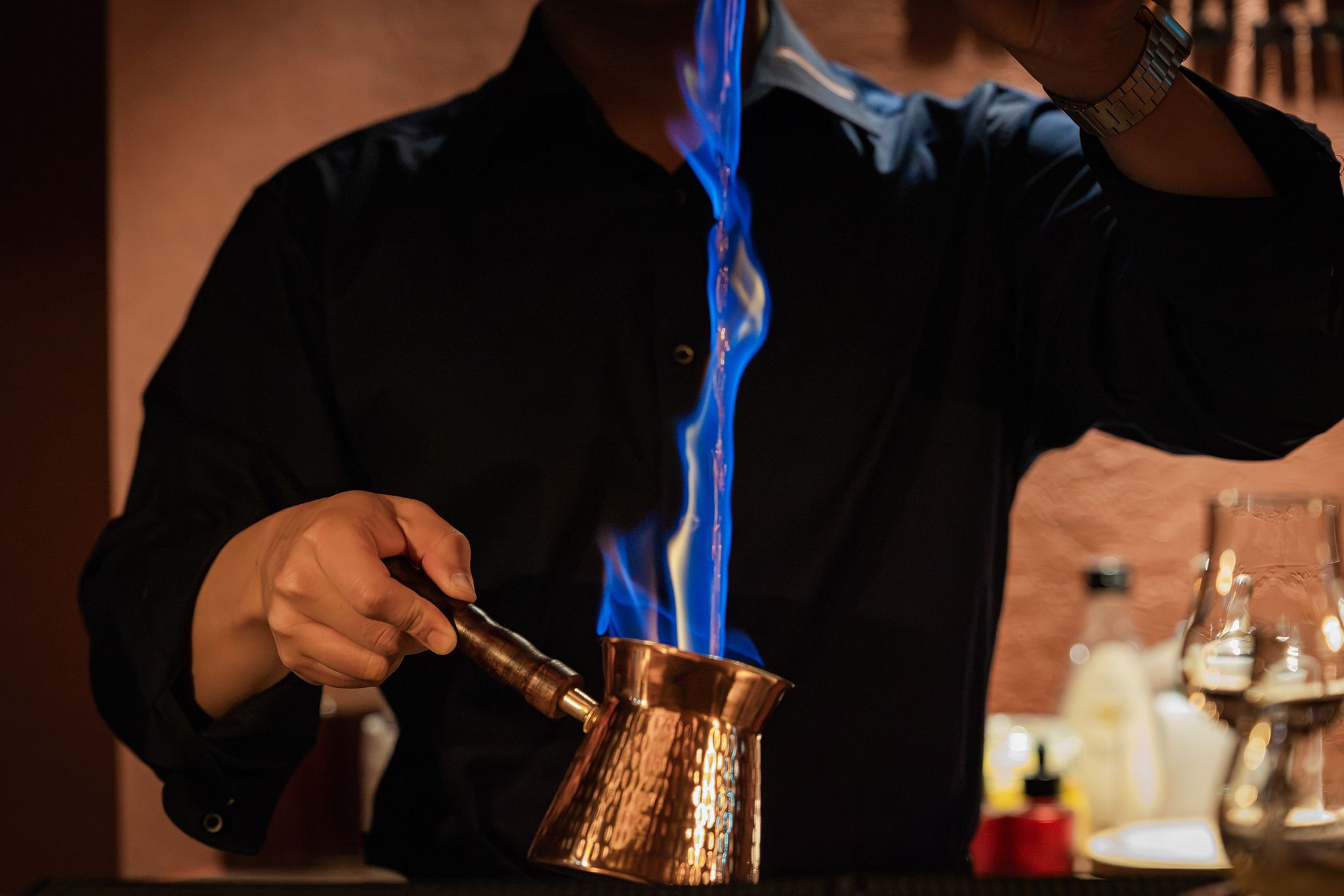 Una persona versa un liquido blu da una pentola di rame.