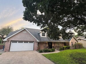 A two-story house with a garage, a covered porch, and a well-maintained lawn. - Red Barn Lake House-Lake McQueeney (Seguin)