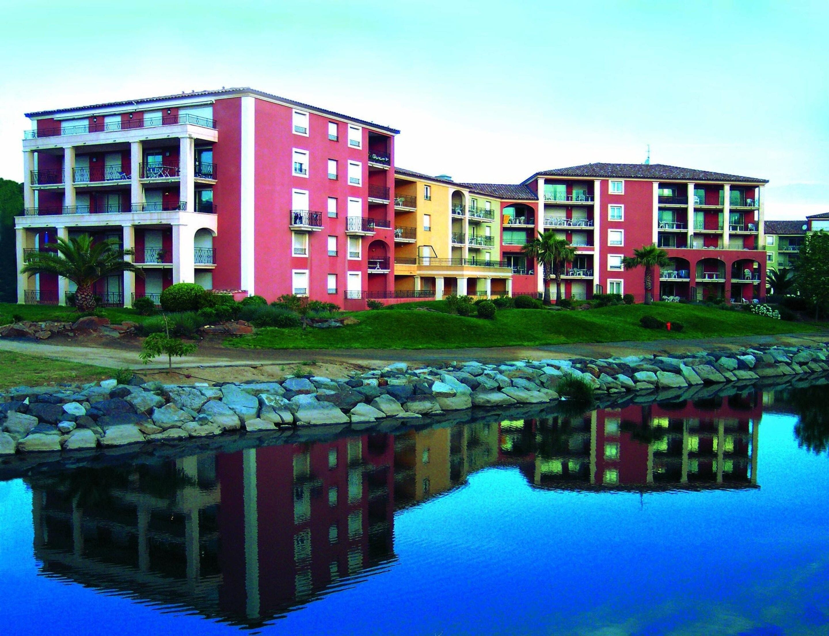 Un hotel de varios pisos con balcones, piscina y el reflejo de los edificios.