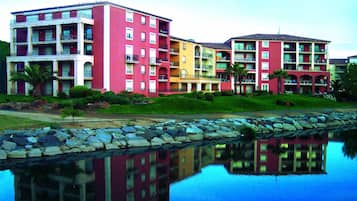 Un hotel de varios pisos con balcones, piscina y el reflejo de los edificios.