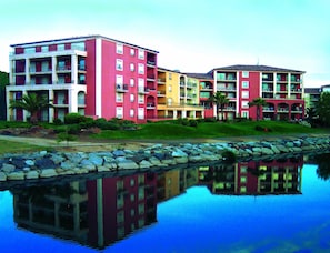 Un hotel de varios pisos con balcones, piscina y el reflejo de los edificios.