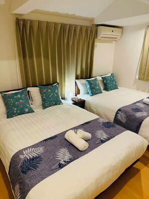 A hotel room with two beds, each with floral pillows, a large window with curtains, and an air conditioning unit on the wall. - Tokyo 3-Story Private House, Sleeps 10, Free Parking, Easy Asakusa & Airports (Katsushika City)