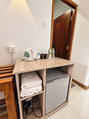 A compact kitchenette with a built-in mini-fridge, a kettle, and a small shelf with towels. - Ruhe Trail Ella (Ella)