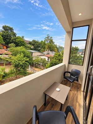 A balcony with a table and two chairs, overlooking a residential area with trees and houses. - Ruhe Trail Ella (Ella)