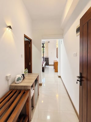 A hallway with a wooden bench, a table with a kettle and bottles, and a door with a key lock. - Ruhe Trail Ella (Ella)