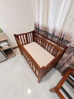 A wooden bed with a striped mattress in a room with white marble flooring and curtains with a striped pattern. - Ruhe Trail Ella (Ella)