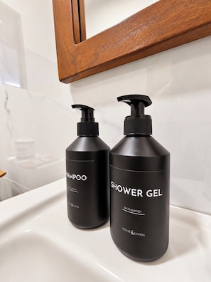 Two black bottles of shampoo and shower gel on a white bathroom sink. - Ruhe Trail Ella (Ella)