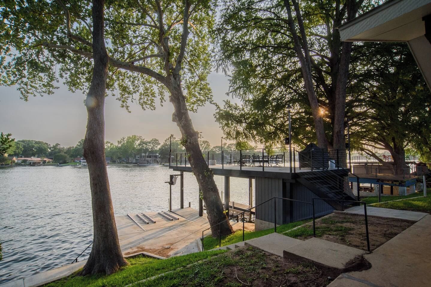 A waterfront property with a dock, outdoor seating, and a staircase leading to a covered area.