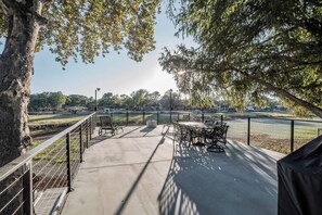 An outdoor patio area with a concrete floor, metal railing, and a table with chairs. - Terminal Wake House-Lake McQueeney (McQueeney)