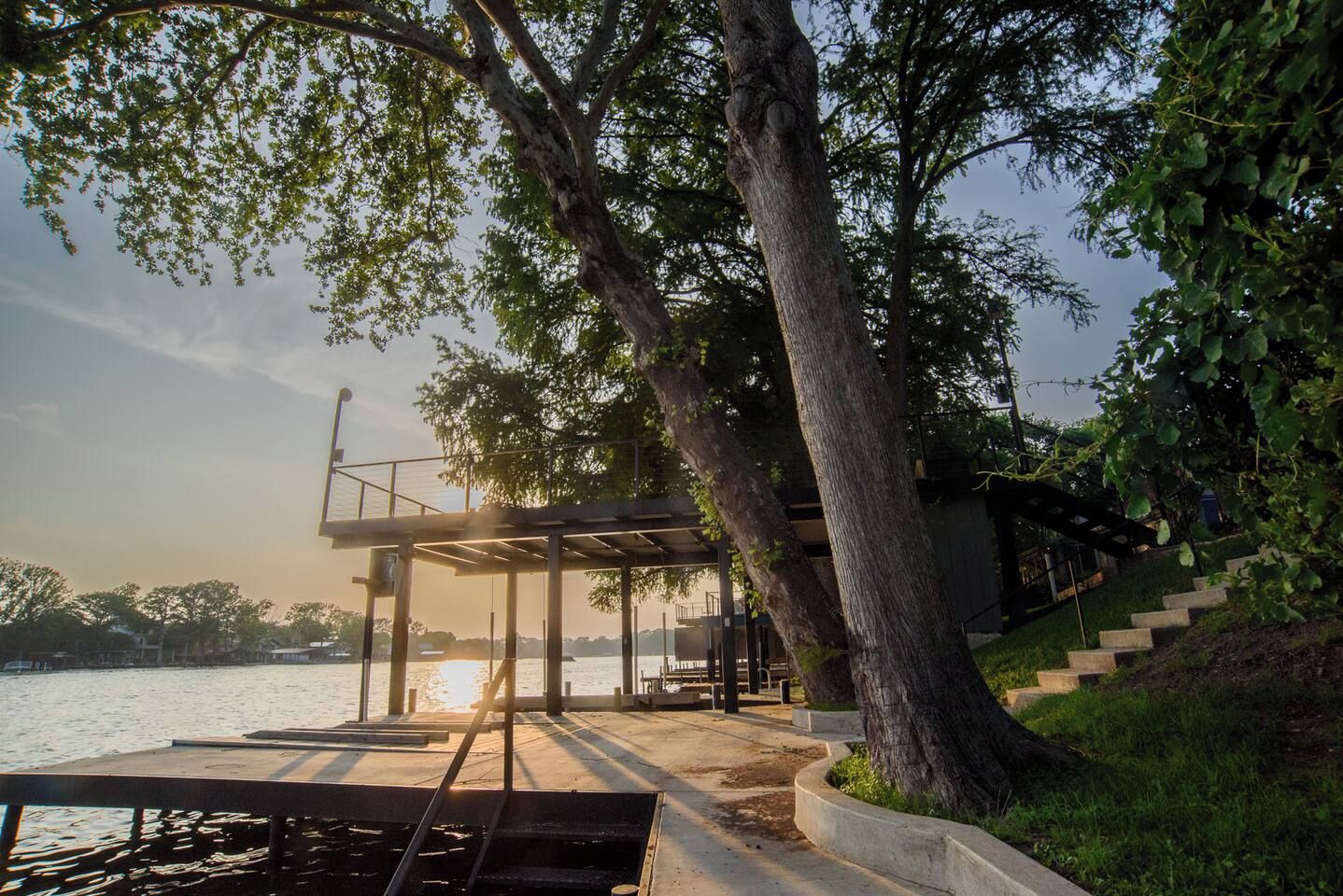 A waterfront deck with a pergola, steps leading down to the water, and a dock.