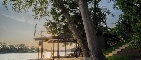 A waterfront deck with a pergola, steps leading down to the water, and a dock.