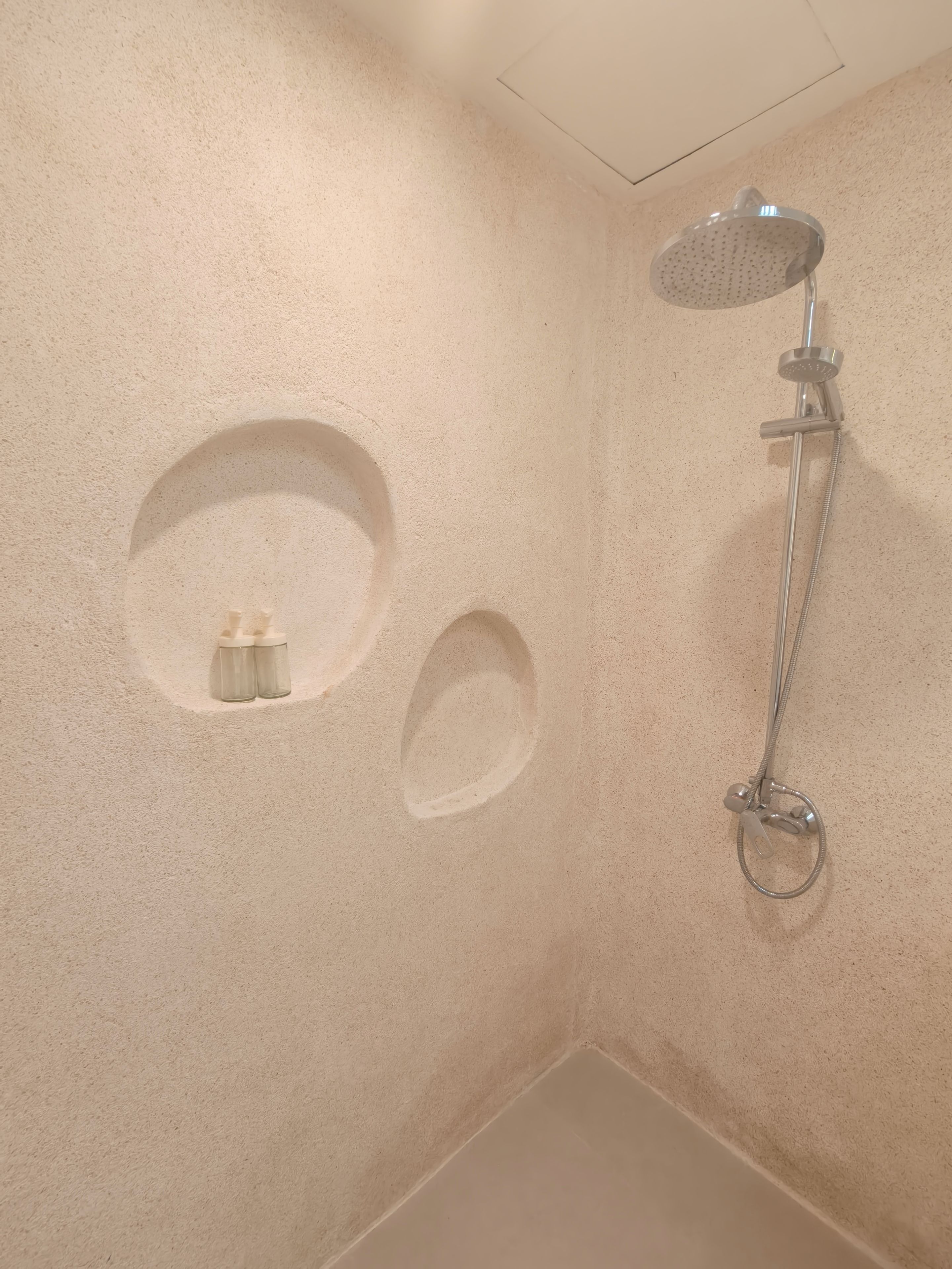 A shower area with a handheld showerhead and a wall-mounted fixture.