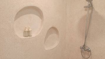 A shower area with a handheld showerhead and a wall-mounted fixture.