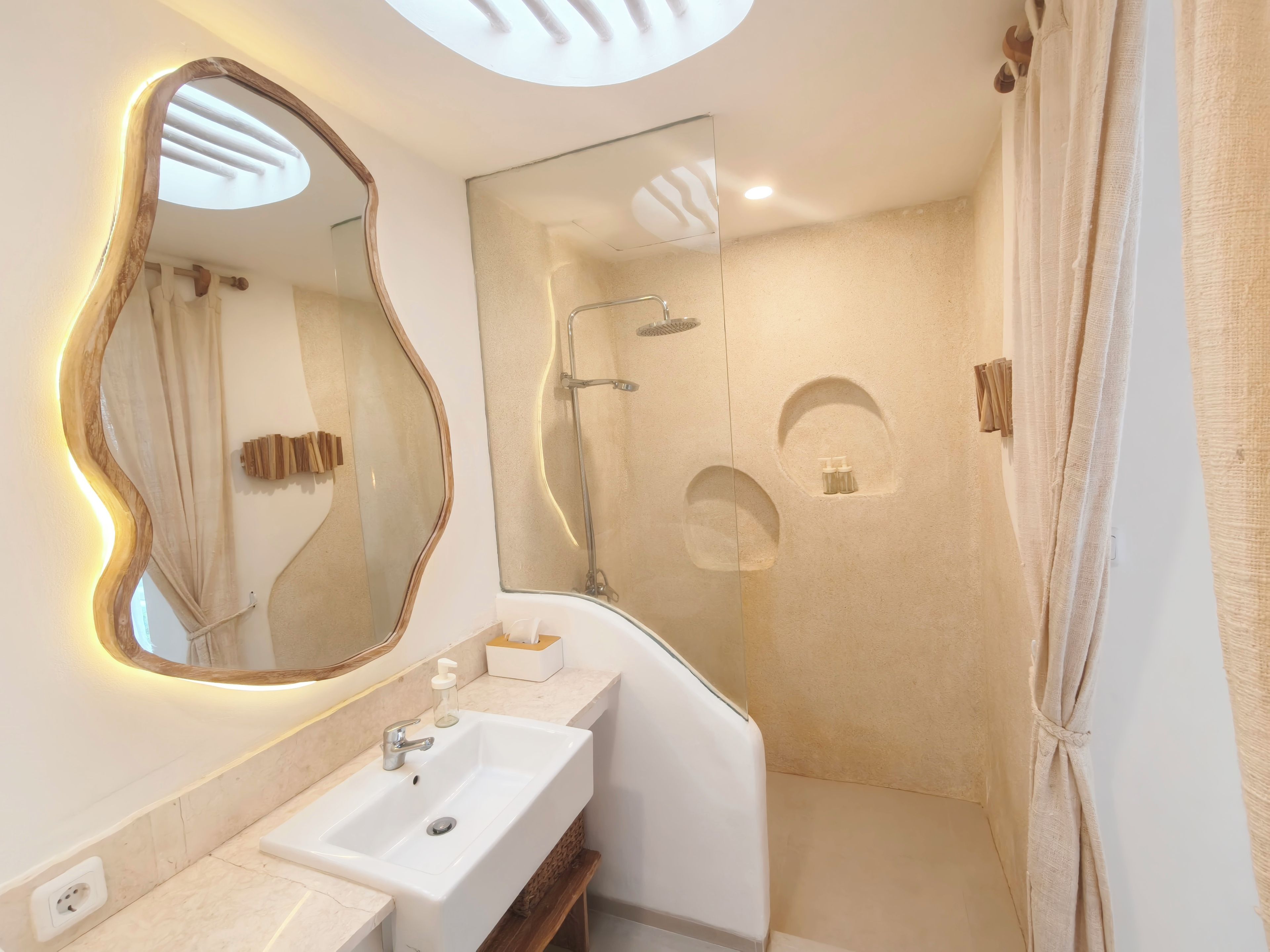 A modern bathroom with a large mirror, a sink, a shower, and a towel rack.