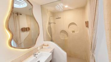 A modern bathroom with a large mirror, a sink, a shower, and a towel rack.