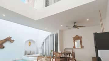 A spacious indoor area with a pool, seating, and a ceiling fan.