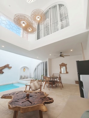 Un amplio espacio interior con piscina, asientos y ventilador de techo.