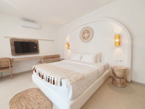 Un dormitorio con cama, escritorio, silla, televisor y luces instaladas en la pared.