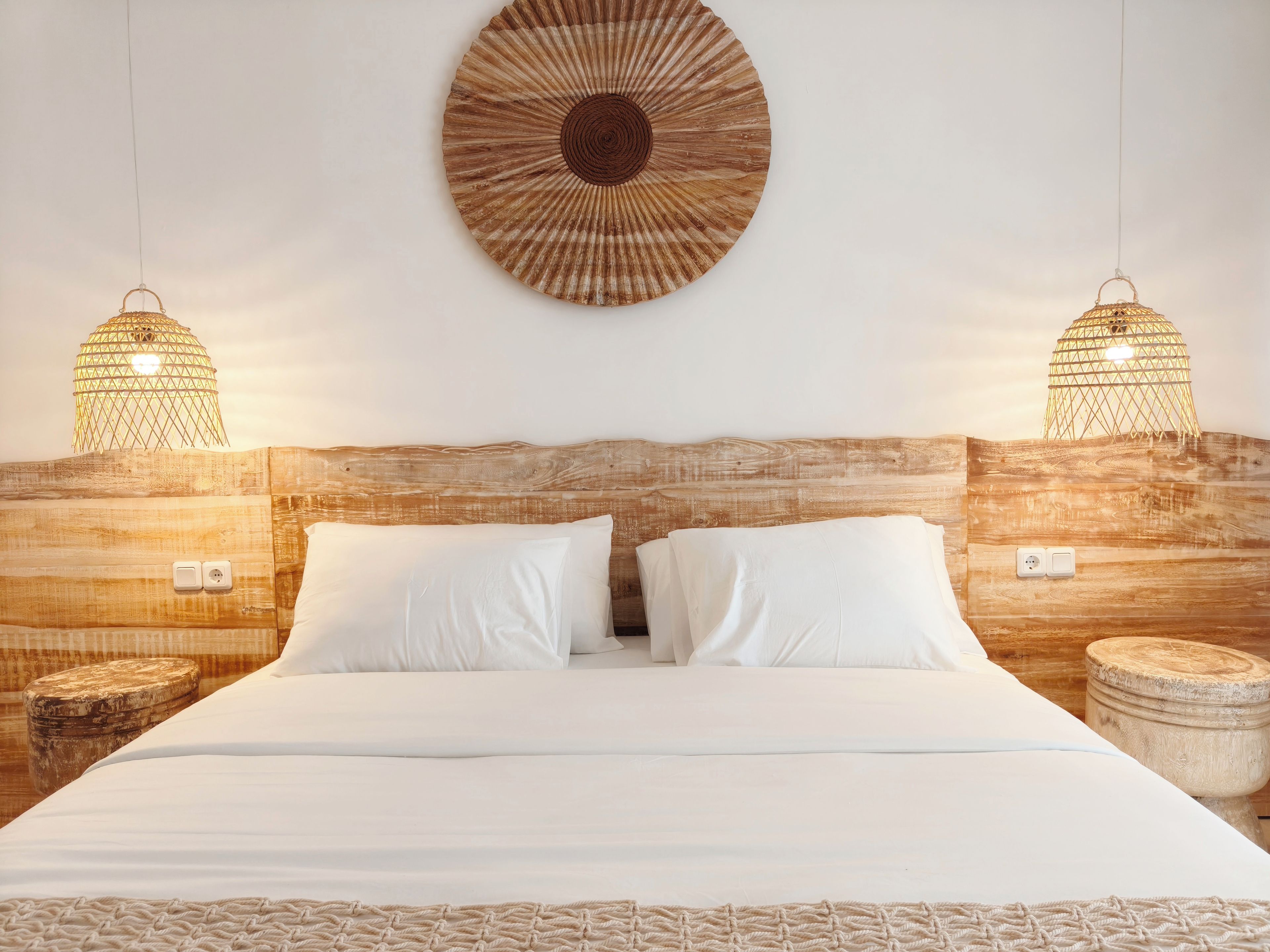 A bed with white linens, two bedside lamps, and a wooden headboard.