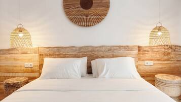 A bed with white linens, two bedside lamps, and a wooden headboard.