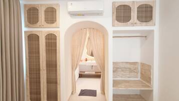 A room with a wooden wardrobe, a white air conditioning unit, and a mirror with a wooden frame.