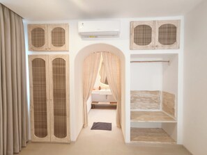 Ein Zimmer mit einem hölzernen Kleiderschrank, einer weißen Klimaanlage und einem Spiegel mit Holzrahmen.