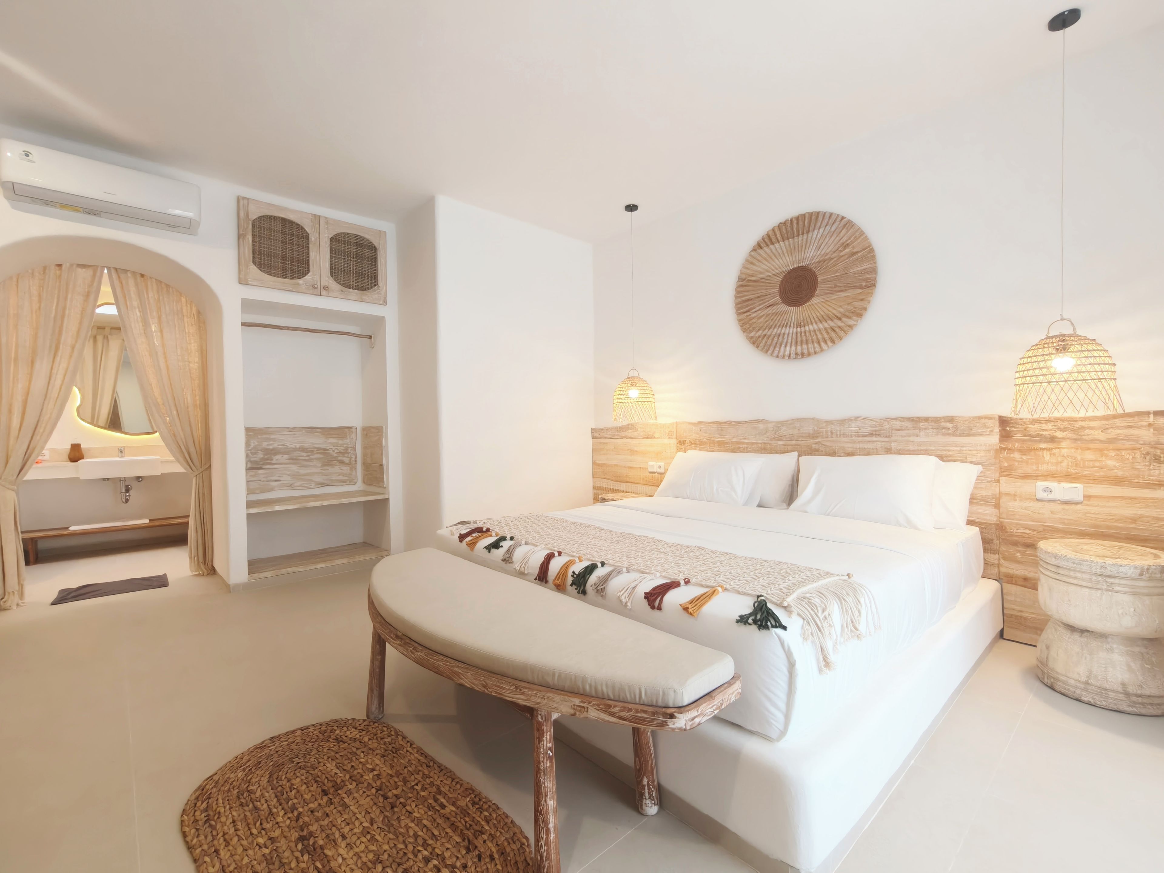 A modern bedroom with a large bed, bedside lamps, a vanity with a mirror, and a hanging light fixture.