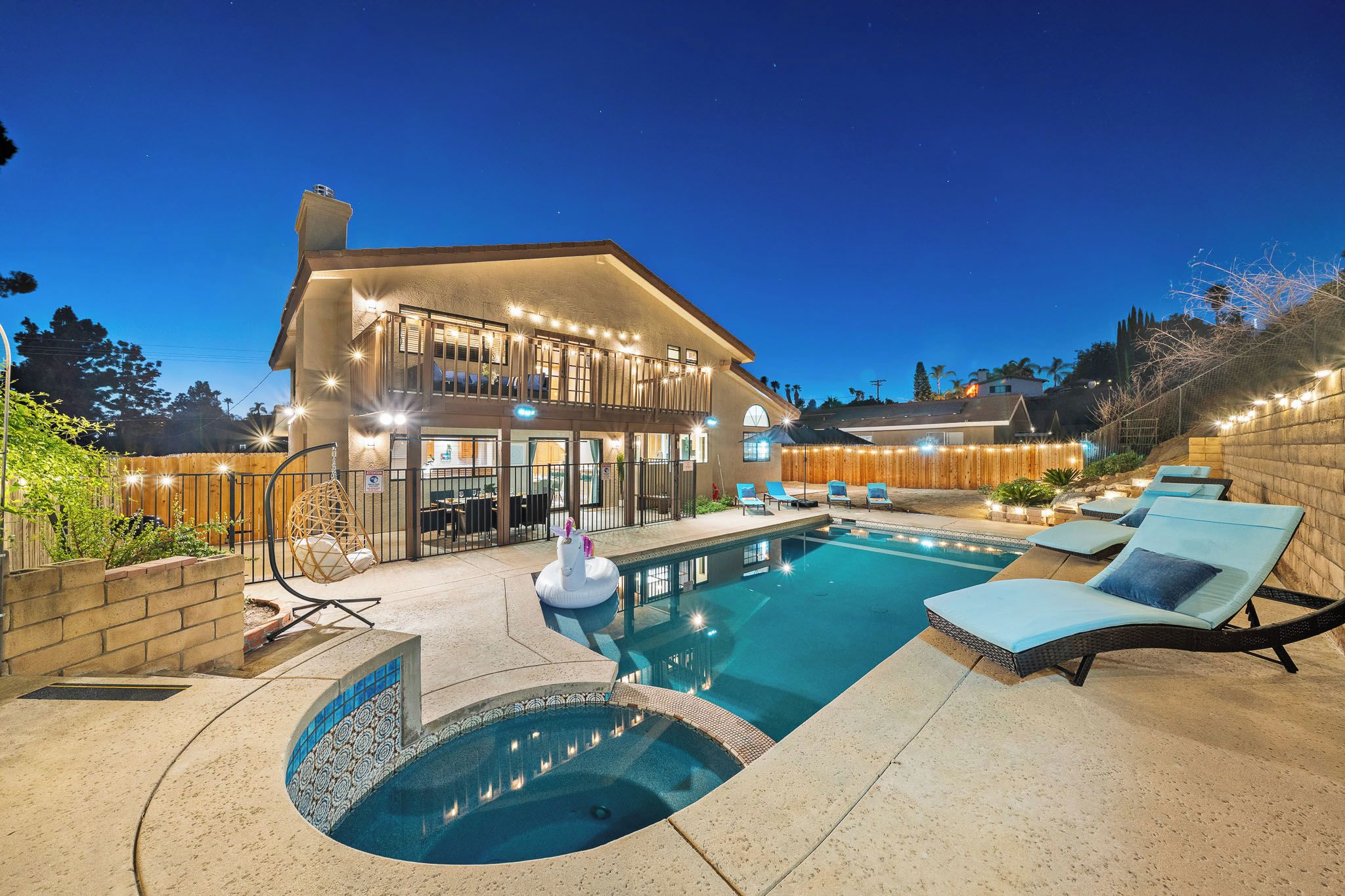 A residential property with a swimming pool, outdoor seating, and a well-lit patio area.