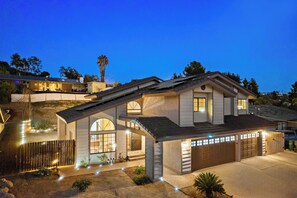 A two-story house with a garage, a driveway, and a well-lit entrance.