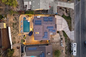 Vista aérea de una propiedad residencial con piscina, paneles solares y un camino de entrada curvo.