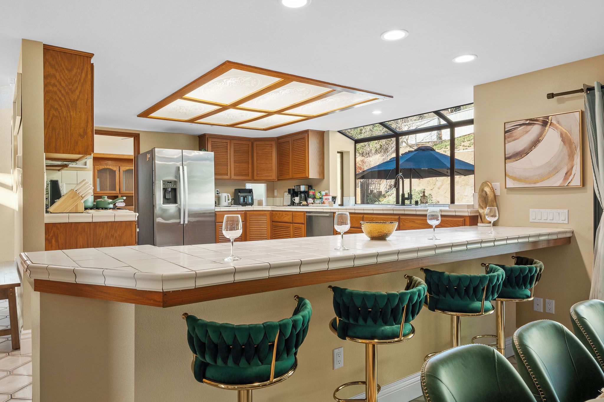 Cozinha moderna com ilha central, banquetas e vista para o exterior.