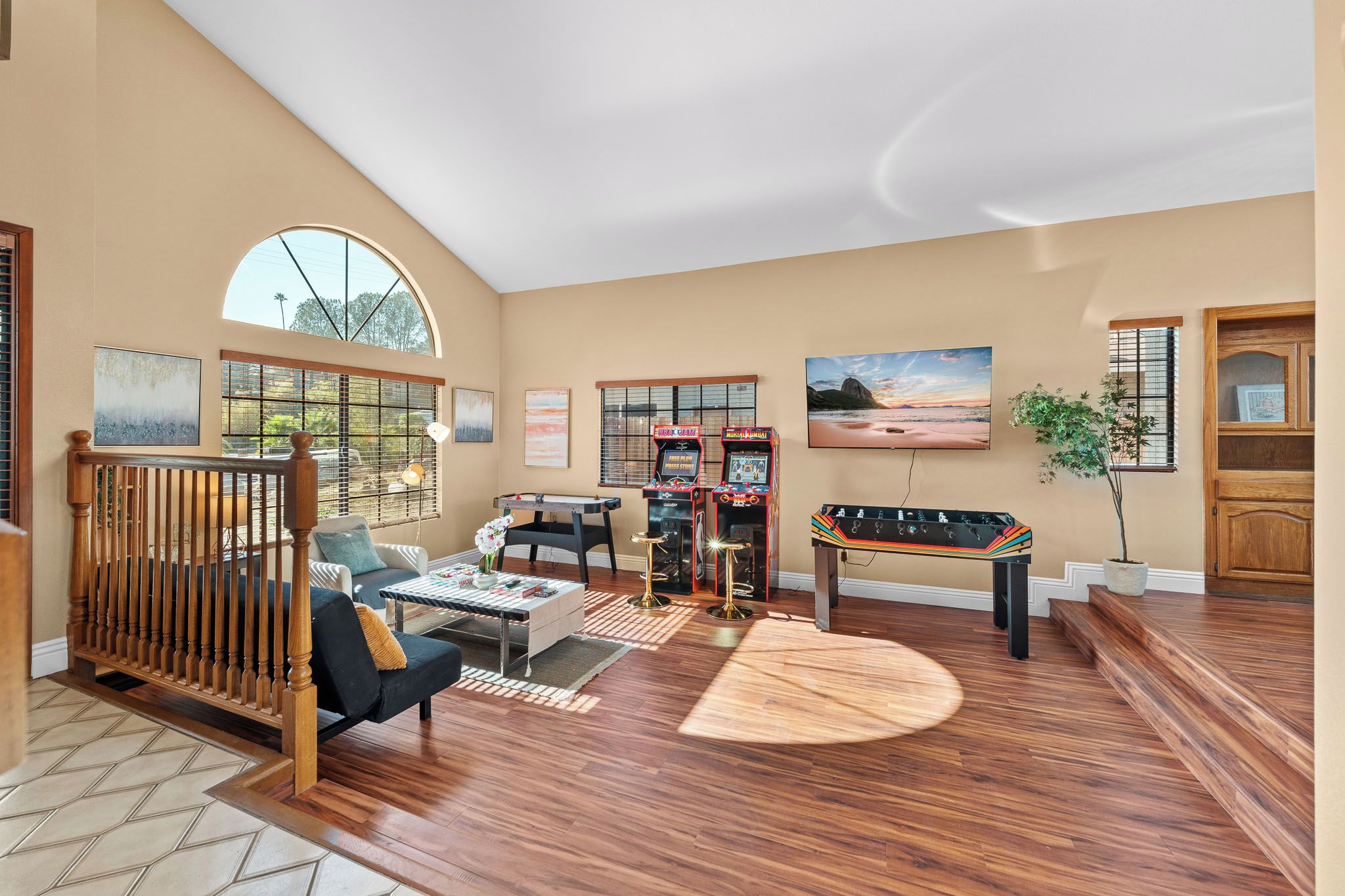 A spacious living room with a pool table, comfortable seating, and large windows.