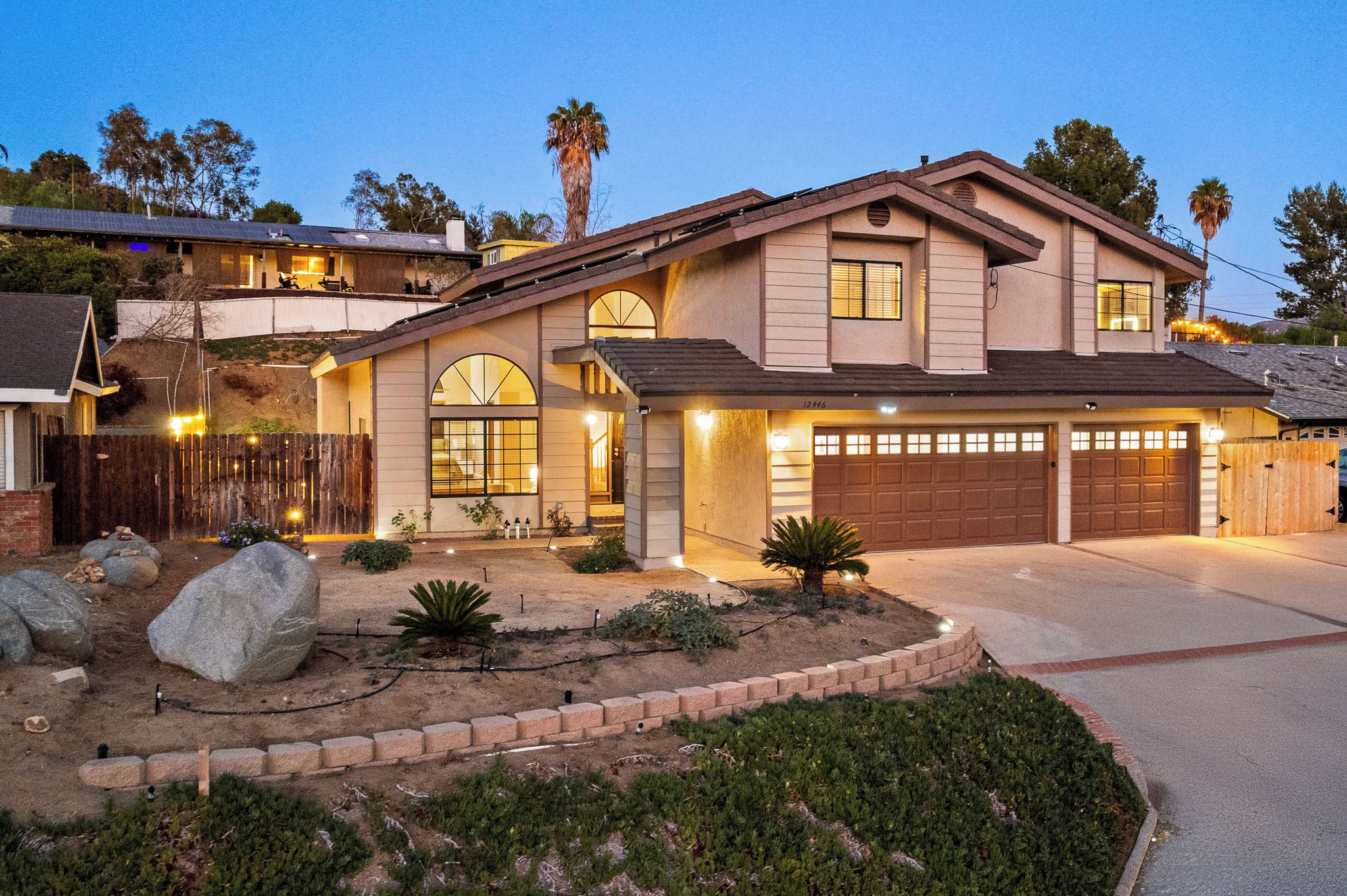 A two-story house with a garage, large windows, and a landscaped front yard.