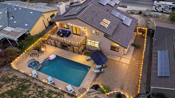 A residential property with a swimming pool, solar panels, and a covered patio area.
