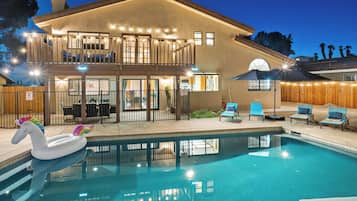 Una casa a due piani con piscina, area relax esterna e un galleggiante a forma di cigno.