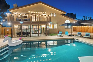 A two-story house with a swimming pool, outdoor seating, and a swan float.