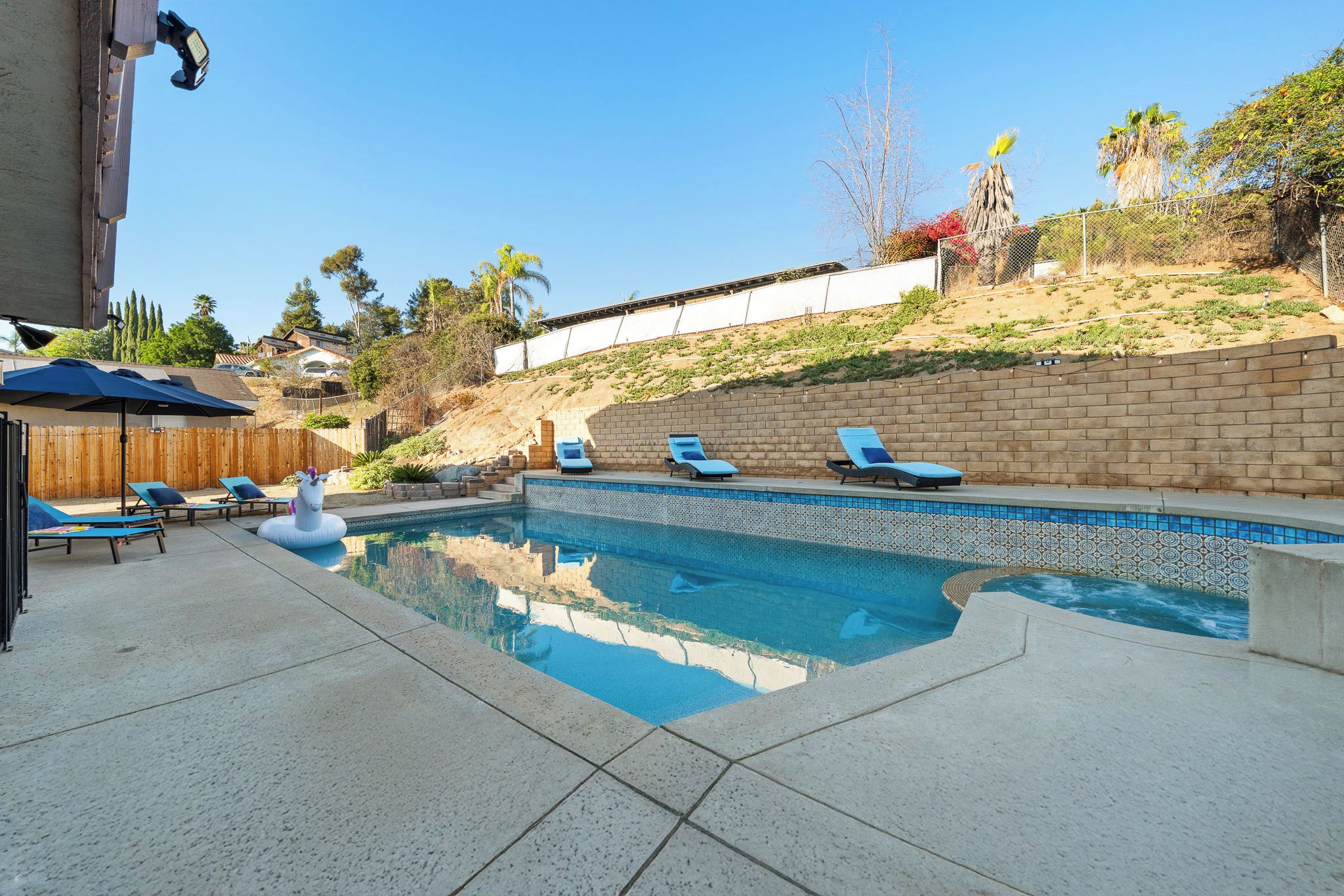 Una piscina con sillas de descanso y un flotador decorativo con forma de unicornio.