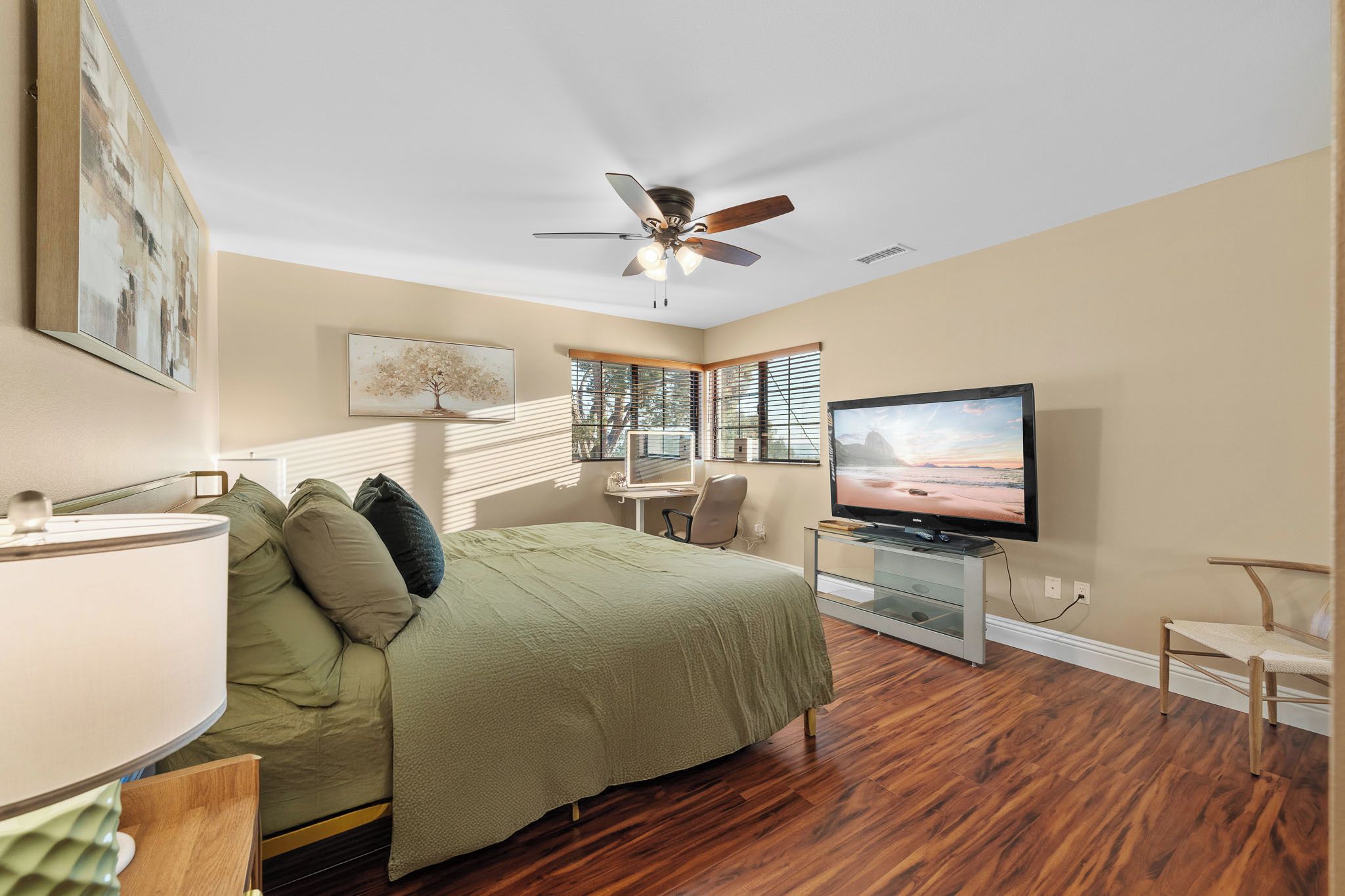 Une chambre à coucher comprenant un lit, un bureau, une chaise, un téléviseur et un ventilateur de plafond.
