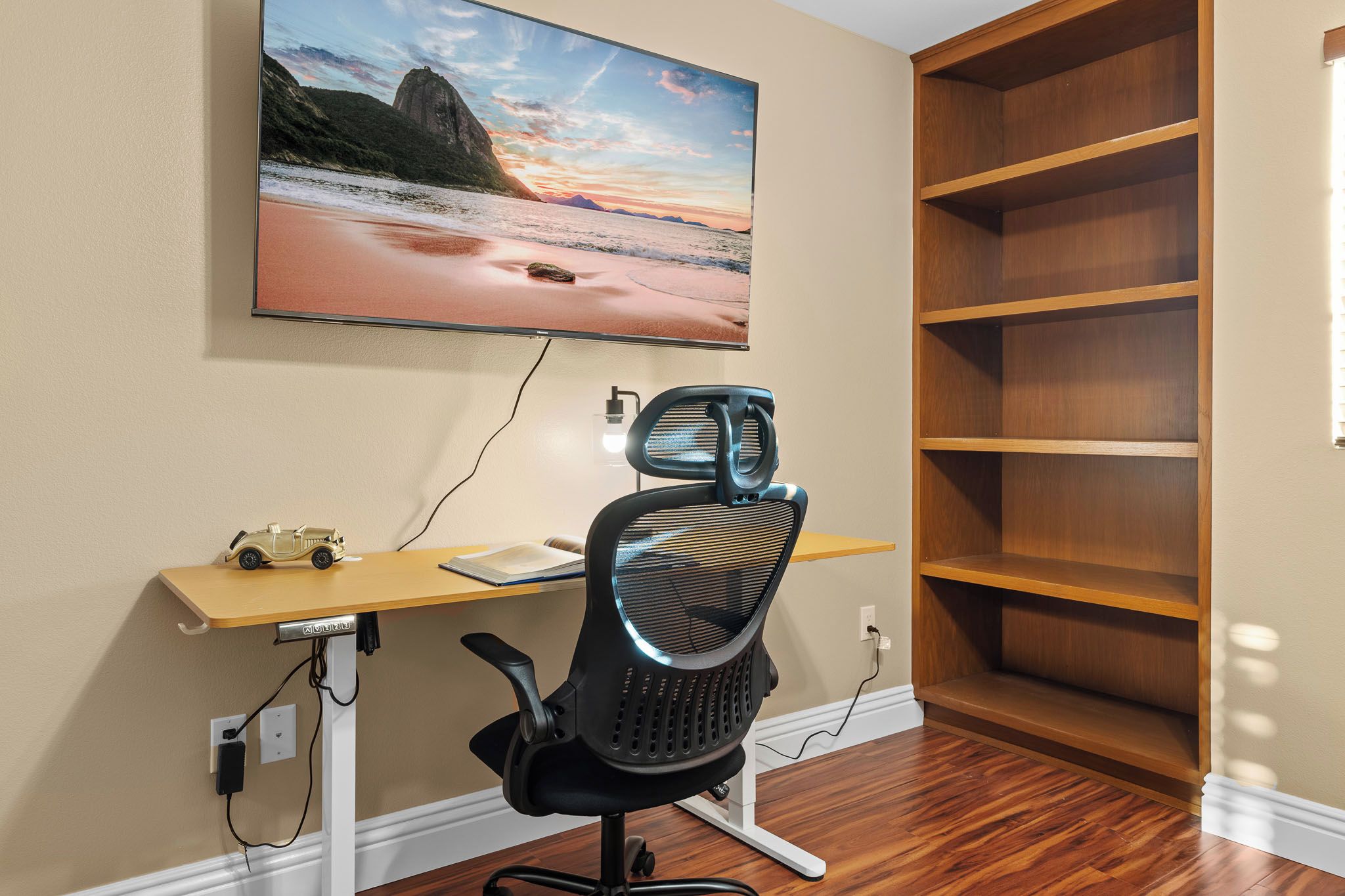 Un espacio de trabajo en casa con escritorio, silla e imagen grande colgada en la pared.