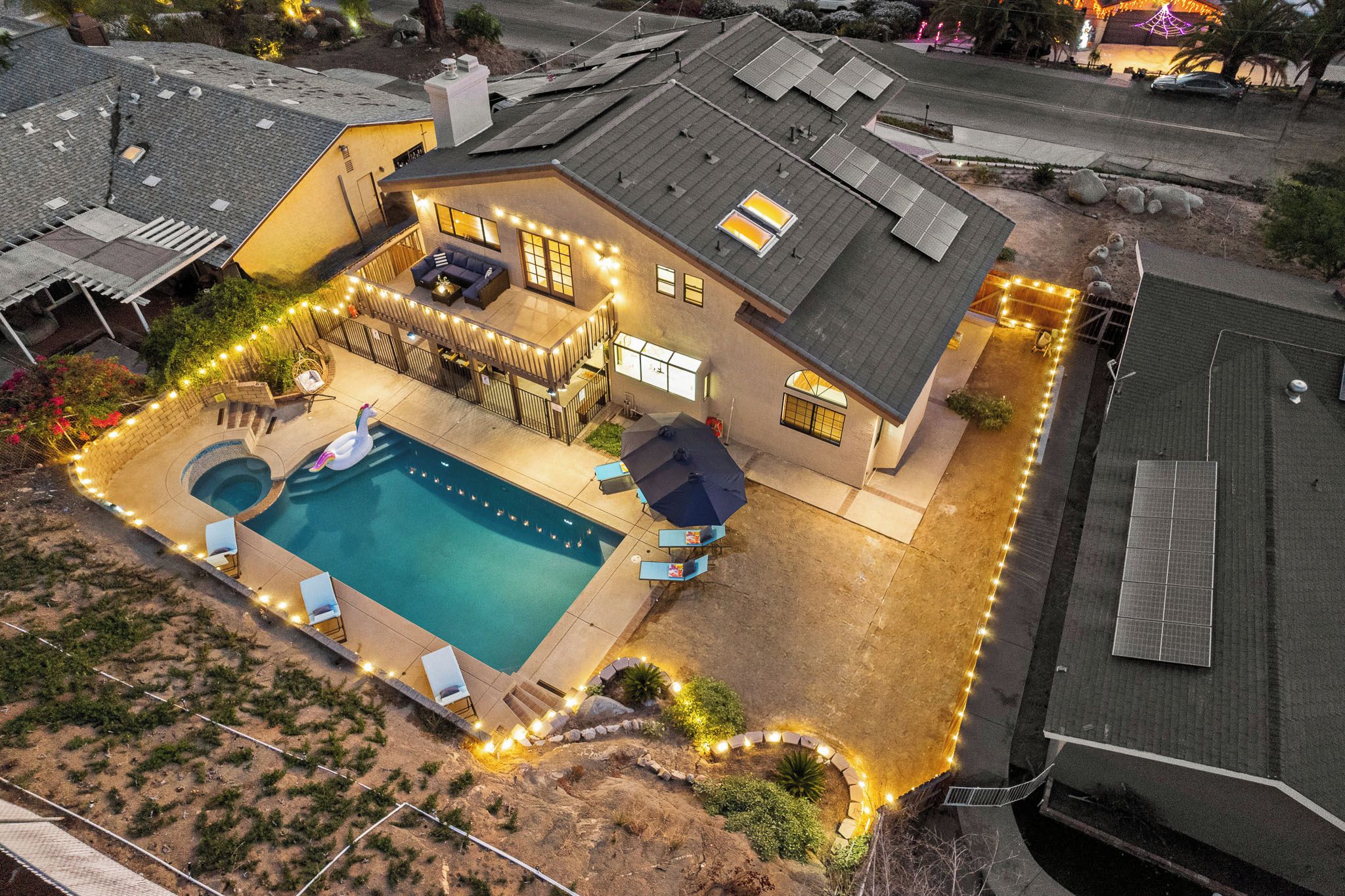 A residential property with a swimming pool, outdoor seating, and solar panels.