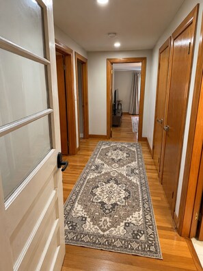 A hallway with wooden flooring, a patterned rug, and wooden doors. - Charming 2-bedroom house in Salem perfect for your getaway (Salem)