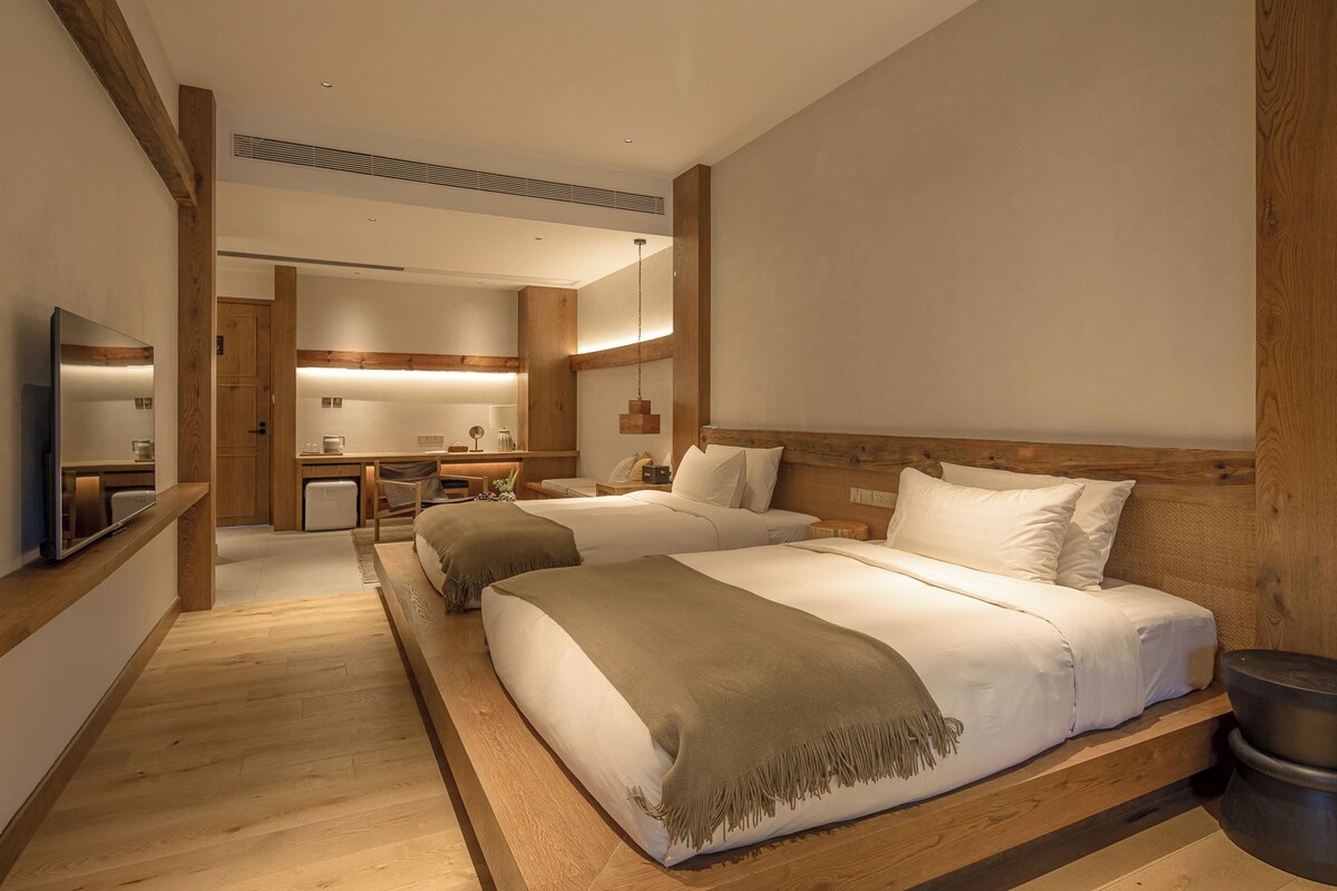 Una habitación de hotel con dos camas, un escritorio, una silla y un televisor.
