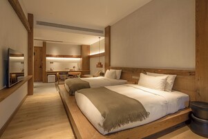 Una habitación de hotel con dos camas, un escritorio, una silla y un televisor.